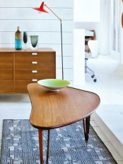 a rich-stained mid-century modern coffee table with a creative shape and on tall legs plus gilded ends is cool