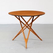a small rich-stained coffee table with a round tabletop and legs that interweave in a creative way