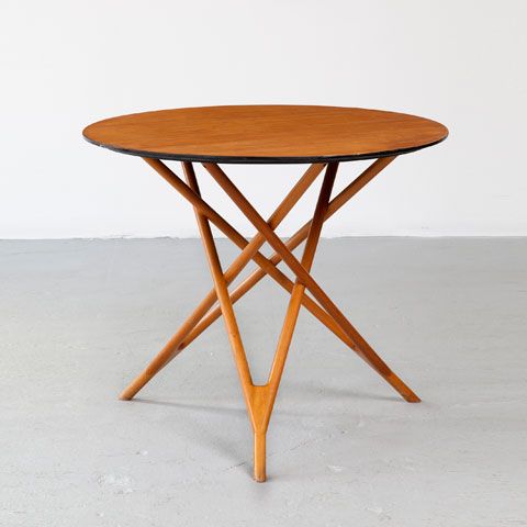 a small rich-stained coffee table with a round tabletop and legs that interweave in a creative way