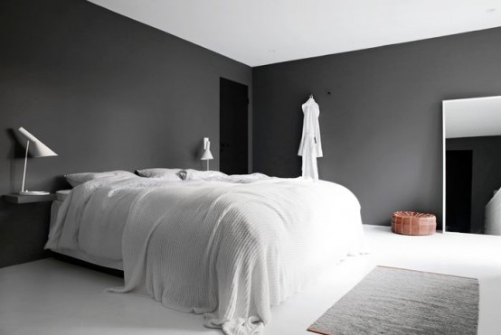 a moody minimalist bedroom with black walls, a white bed with bedding, black nightstands and white table lamps