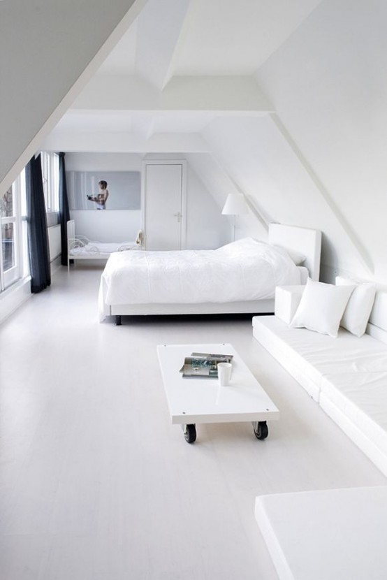 a minimalist white bedroom with a white bed, a white corner sofa, a coffee table on casters and a smaller bed for a kid is cool