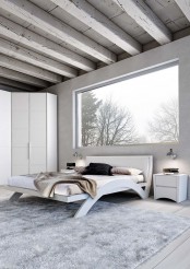a neutral minimalist bedroom with a whitewashed ceiling with beams, white minimalist furniture, neutral textiles and a view