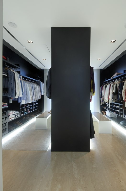 a large minimalist closet done in black and white, with lots of holders and open shelves plsu drawers and built in lights