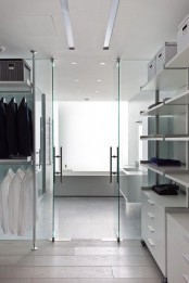 a minimalist closet done in white, with holders for clothes hangers and open shelves plus boxes plus glass doors