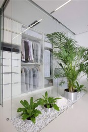 a small minimalist closet with lots of drawers and cubbies plus open holders for clothes and glass walls