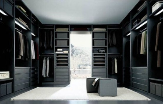 a minimalist closet done in black, with a white rug in the center and lots of drawers and open shelving