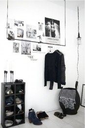 a minimalist closet with a holder for hangers, a black storage unit, a basket and a pendant lamp over it all