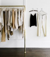 a stylish makeshift closet in gold with some holders for clothes hangers is a simple and modern idea