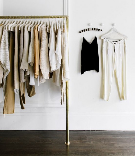 a stylish makeshift closet in gold with some holders for clothes hangers is a simple and modern idea
