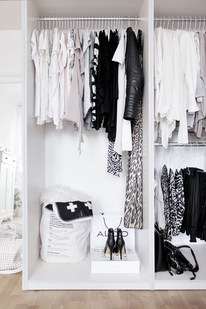 a simple minimalist white closet with open holders and some baskets for small stuff