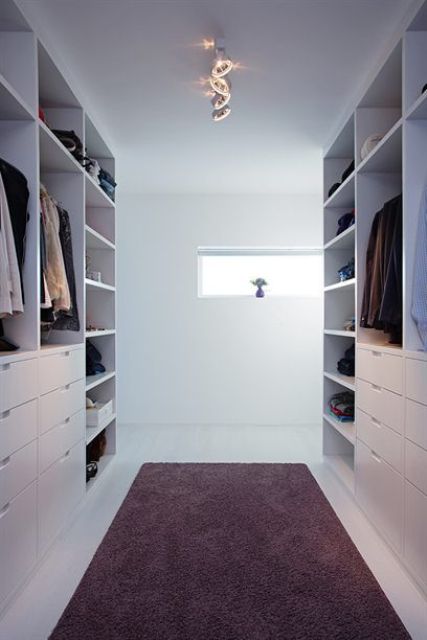 a minimalist white closet with open shelves, holders and drawers for small stuff plus a rug in the center