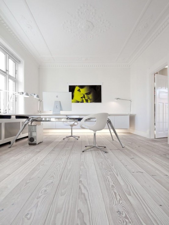 a neutral minimalist home office with a floating storage unit with built-in lights, a long desk, white chairs and white gadgets plus table lamps here and there