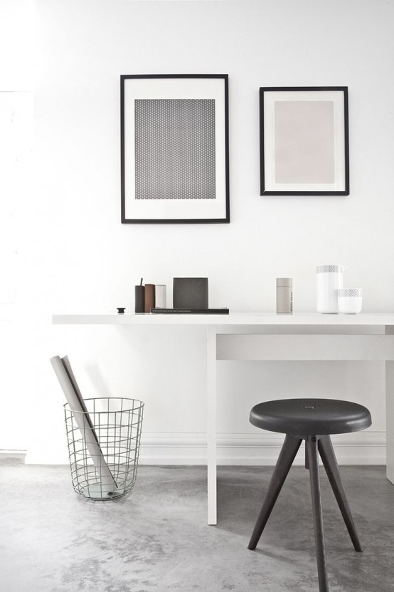 a black and white minimalist home office with a sleek white desk, a black stool, a small gallery wall and a bit of decor