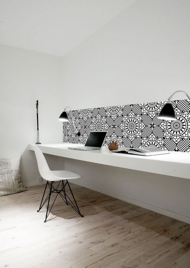 a stylish minimalist home office with a long floating desk, black sconces and a mosaic tile backsplash plus a white chair