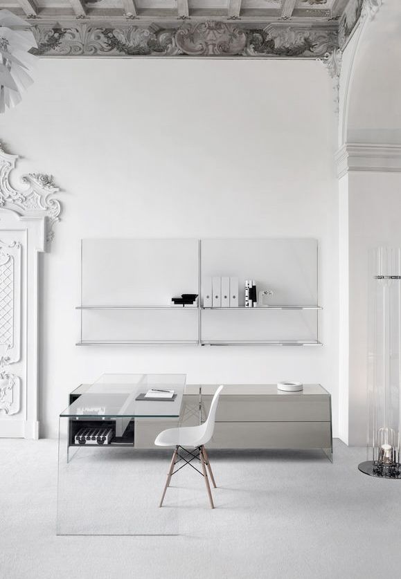a pure minimalist home office with open shelves, a sleek storage unit, a glass desk and a white chair, some candles and chic decor around