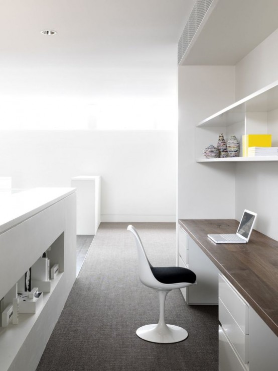 a minimalist home office with a built-in storage unit and a desk in it, a comfy white chair and a large storage unit with a niche