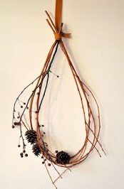 a modern and simple Thanksgiving decoration of twigs and pinecones can be hung on the wall or front door