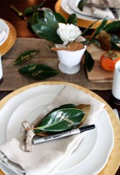 a modern rustic table setting with a burlap runner, foliage, simple plates and chargers