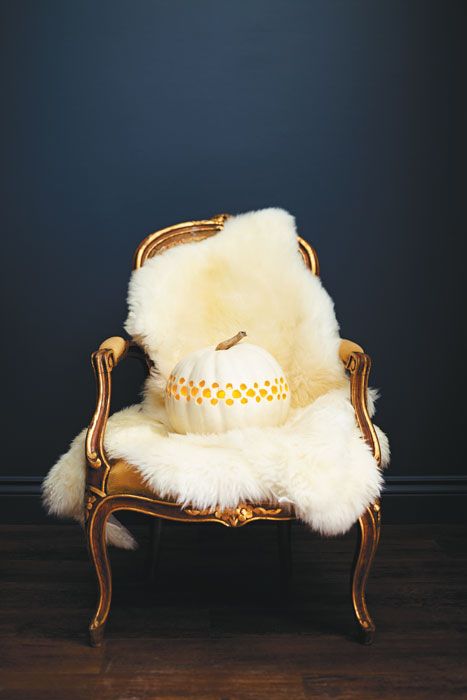a refined chair with white fur and a large white carved pumpkin is a simple and stylish Thanksgiving decoration