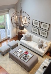 a neutral modern farmhouse living room with grey walls, grey and white seating furniture, a mini gallery wall and a sphere chandelier is great and welcoming