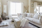 a neutral living room with beige walls, creamy seating furniture, upholstered ottomans and neutral linens is flowy and welcoming