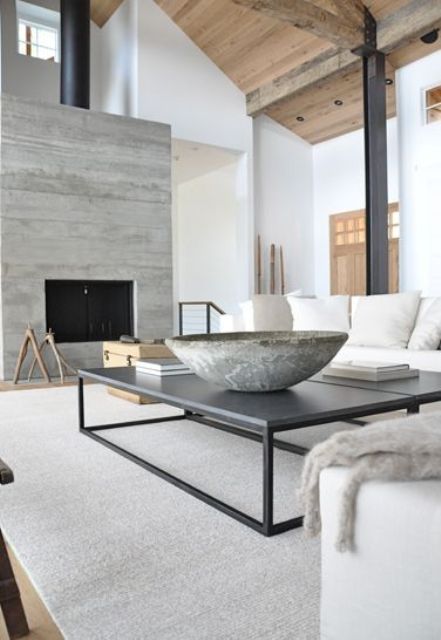 a neutral contemporary living room with a built in fireplace, neutral seating furniture, a contemporary black coffee table, a stone bowl and a stone accent wall