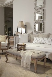 a glam neutral living room in white, grey and silvery greys, with refined and chic furniture, mirrors in ornated frames and lamps and baskets