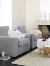 a refined neutral living room with a fireplace clad with brick, light blue chairs, neutral textiles, mismatching side tables