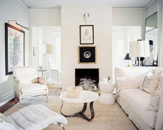 a refined neutral living room with a built-in fireplace, neutral refined furniture, chic artworks and mirrors in ornated frames and neutral textiles is amazing