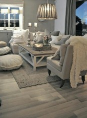 a neutral grey, creamy and silver living room with a sectional, a chair, lots of cushions and pillows and pendant lamps