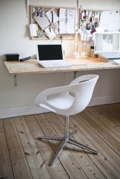 a Scandinavian home office in neutrals, with a memo board, a wall-mounted desk, a white chair, some art and other stuff