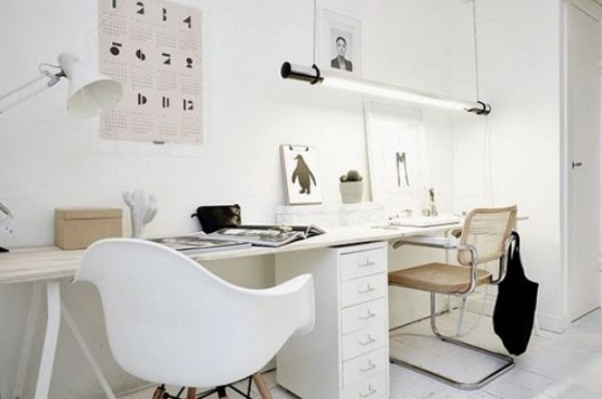 a shared white Nordic home office with a large shared trestle desk, white and neutral chairs, pendant and table lamps and artwork