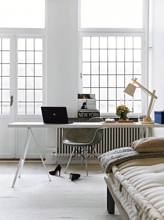 a white Scandinavian home office with a wooden desk, a grey chair, a wooden table lamp and potted plants flooded with light