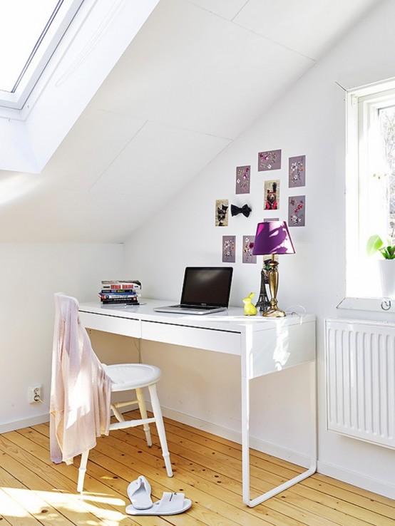 a white home office with a laconic desk and a chair, a gallery wall, a purple table lamp and lots of natural light