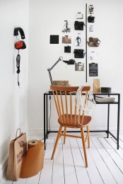 a black and white Scandinavian home office with a black IKEA desk, a wooden chair, a gallery wall and a holder for earphones