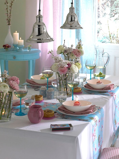 a bright pink and blue spring tablescape with blooms, candles and colorful porcelain