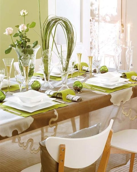 a green and white sprign table setting with green placemats, greenery and bloom centerpieces and little terrariums
