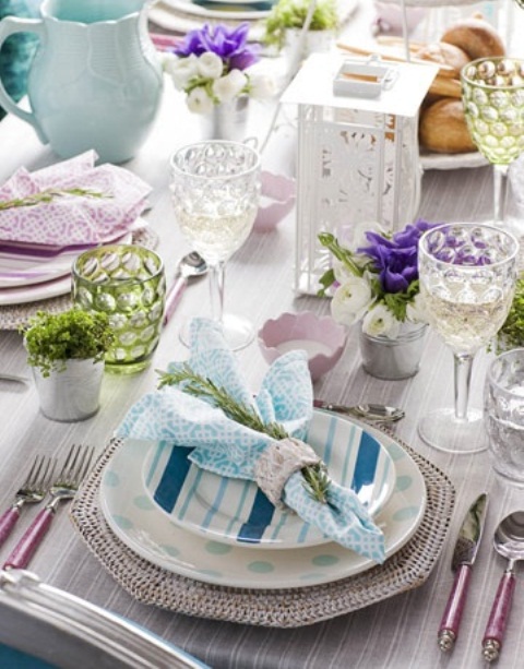 a pastel place setting with printed plates and chargers, pastel glasses, greenery and moss