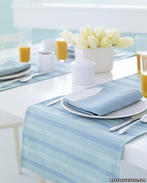 a pastel spring tablescape in powder blue and white, with striped textiles and a neutral floral centerpiece