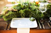 a modern place setting with a lush fern, moss and greenery centerpiece