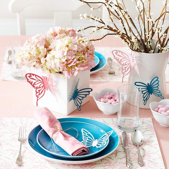 a pink and blue place setting with bright plates, hydrangeas and butterflies