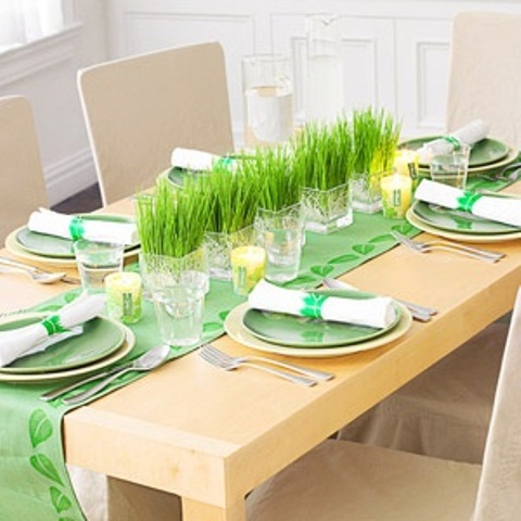 a bright green spring tablescape with a green runner and plates and fresh grass centerpieces