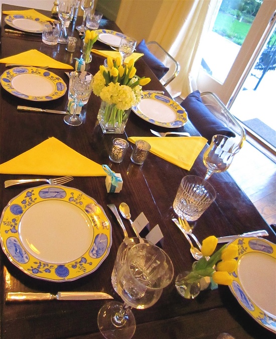 a simply bright spring tablescape with yellow napkins, yellow tulips, patterned plates