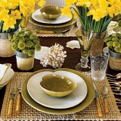 a place setting with a burlap placemat, yellow bloom centerpieces