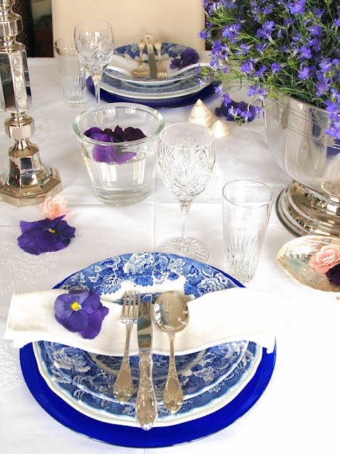 a spring place setting with printed blue plates and purple blooms