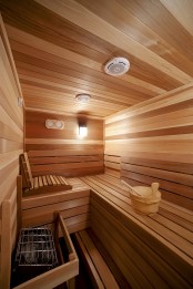 a super cozy steam room clad with wood, with benches at various levels and some built-in lights