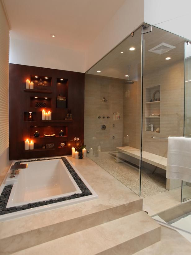 a large neutral steam room with various neutral tiles on the floor and walls, built in shelves and a bench plus built in lights and glass walls