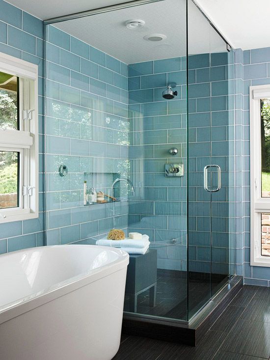 a small steam room with blue and black tiles, with a built-in niche for storage and a bench of wood