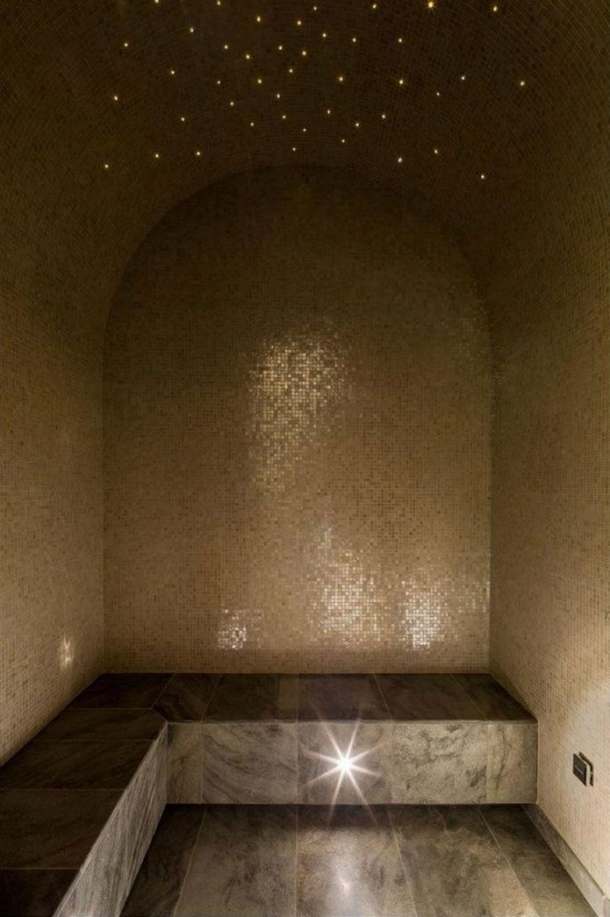 a neutral steam room clad with grey tiles on the bench and floor and lights resembling of a night sky