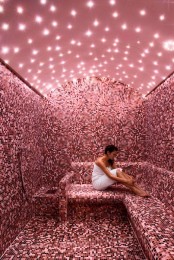 a pink steam room clad with mosaic tiles and with built-in lights that show off a sky is very romantic